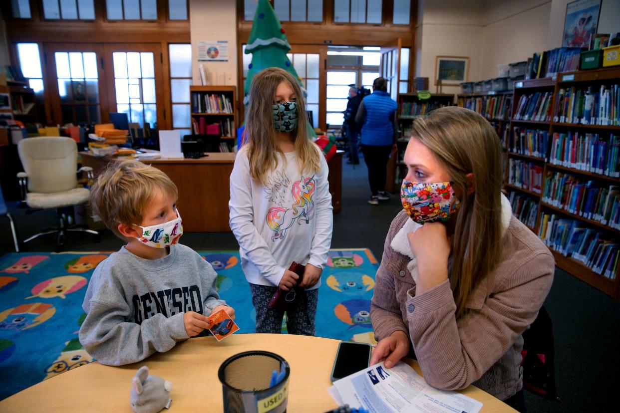 George, 6, left, and his sister, Coralina, 9, center, wait with their mother, Amanda Betette, after getting their COVID-19 vaccination at Hartford University School, Milwaukee, in 2021.