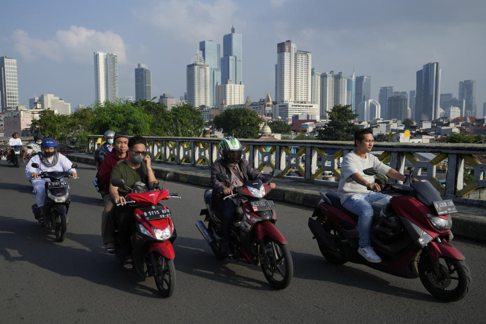 Men ride their motorbikes with the city skyline in the background, in Jakarta, Indonesia, Monday, Feb. 12, 2024. When millions of Indonesians pick their new president in one of the world's biggest elections on Feb. 14, the United States and China would be closely watching who will next lead a key Asian battleground coveted for its huge market, nickel and voice. (AP Photo/Achmad Ibrahim)