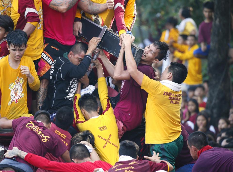 Filipino Roman Catholic devotees climb the carriage to kiss and rub with their towels the image of the Black Nazarene to celebrate its feast day Monday, Jan. 9, 2017 in Manila, Philippines. The raucous celebration drew tens of thousands of devotees in a barefoot procession for several hours around Manila streets and end up with several people injured. (AP Photo/Bullit Marquez)