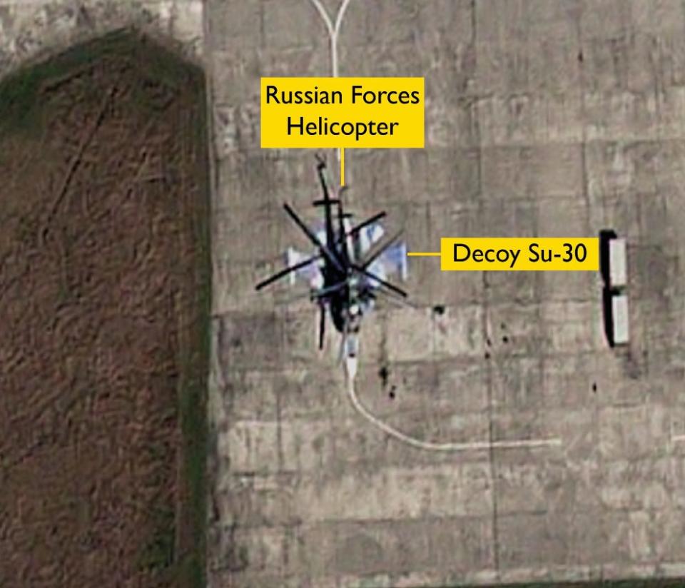 A Russian helicopter on top of a decoy fighter jet at a Russian base in Crimea.