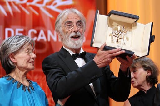 Austrian director Michael Haneke raises his trophy as he poses with French actress Emmanuelle Riva after being awarded with the Palme d'Or for his film "Amour" during the closing ceremony of the 65th Cannes film festival in Cannes