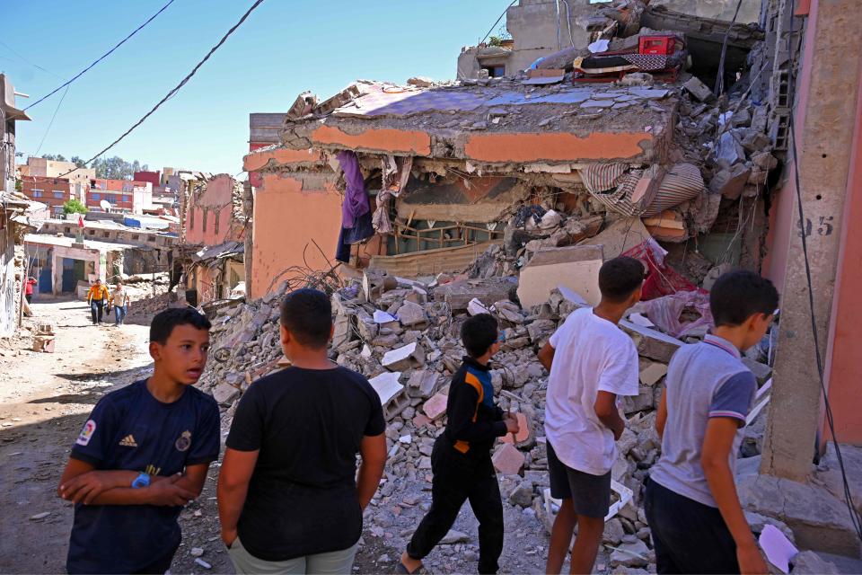 People walk past a destroyed house near Amizmiz in Morocco's worst-hit province of al-Haouz on Sept. 11, 2023, following a 6.8-magnitude quake. Medics treated a constant flow of casualties after Morocco's strongest-ever earthquake killed more than 2,800 people, but on Sept. 12, hopes of finding more survivors under the rubble were fading.