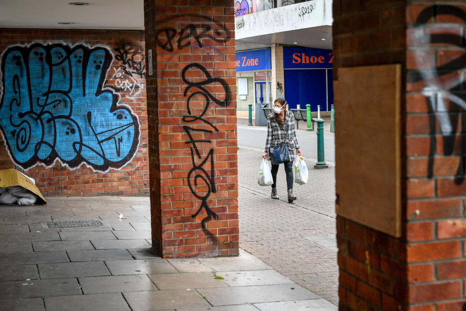 A woman wearing a face mask carries shopping through the High Street in Bedminster, Bristol as the UK continues in lockdown to help curb the spread of the coronavirus.