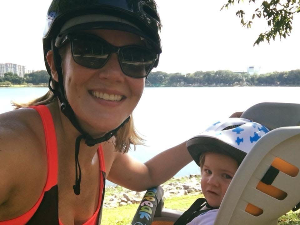 Woman and young boy in a baby seat on a bicycle.