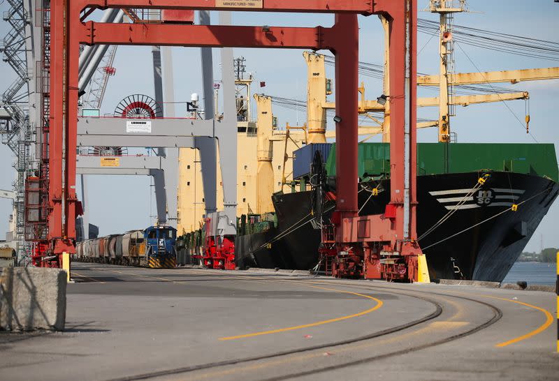 A Port train carrying shipping containers pulls up beside a cargo ship in the Port of Montreal