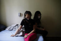 Women sit on a bed at a religious institution being used as a government-run shelter where citizens returning home are required by law to quarantine for two weeks and pass two consecutive COVID-19 tests, as a preventive measure amid the COVID-19 pandemic near Asuncion, Paraguay, Thursday, June 18, 2020. Along with Paraguay's relative isolation, experts credit the country's success at containing COVID-19 with creating a network of quarantine centers where citizens arriving home must isolate. (AP Photo/Jorge Saenz)