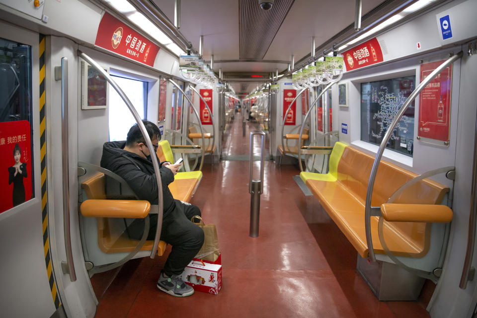 In this Sunday, Jan. 26, 2020 photo, a man wearing a face mask rides in a nearly empty subway train in Beijing. Fears of a virus outbreak have kept many indoors and at home in China's capital. Cultural landmarks such as the Great Wall and Forbidden City have closed their doors to visitors, nearly deserted shopping malls have reduced their operating hours, and restaurants that remain open draw just a handful of customers. (AP Photo/Mark Schiefelbein)