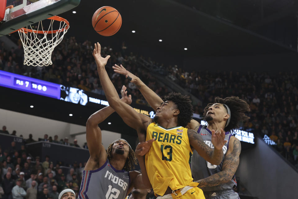 Baylor guard Langston Love (13) scores between TCU forward Xavier Cork (12) and TCU guard Micah Peavy (0) during the first half of an NCAA college basketball game Saturday, Jan. 27, 2024, in Waco, Texas. (AP Photo/Jerry Larson)