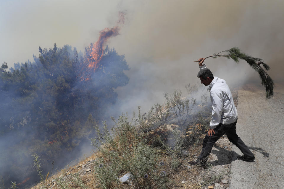 A man tries to extinguish a forest fire, at Qobayat village, in the northern Akkar province, Lebanon, Thursday, July 29, 2021. Lebanese firefighters are struggling for the second day to contain wildfires in the country's north that have spread across the border into Syria, civil defense officials in both countries said Thursday. (AP Photo/Hussein Malla)