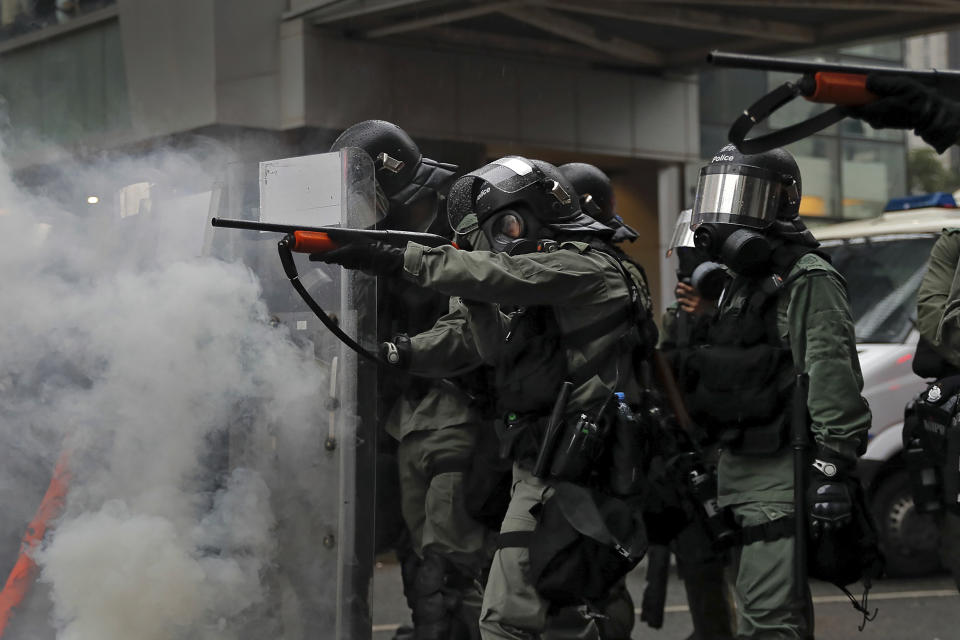 Riot policemen point weapons during a confrontation with demonstrators during a protest in Hong Kong, Sunday, Aug. 25, 2019. Hong Kong police have rolled out water cannon trucks for the first time in this summer's pro-democracy protests. The two trucks moved forward with riot officers Sunday evening as they pushed protesters back along a street in the outlying Tsuen Wan district. (AP Photo/Kin Cheung)