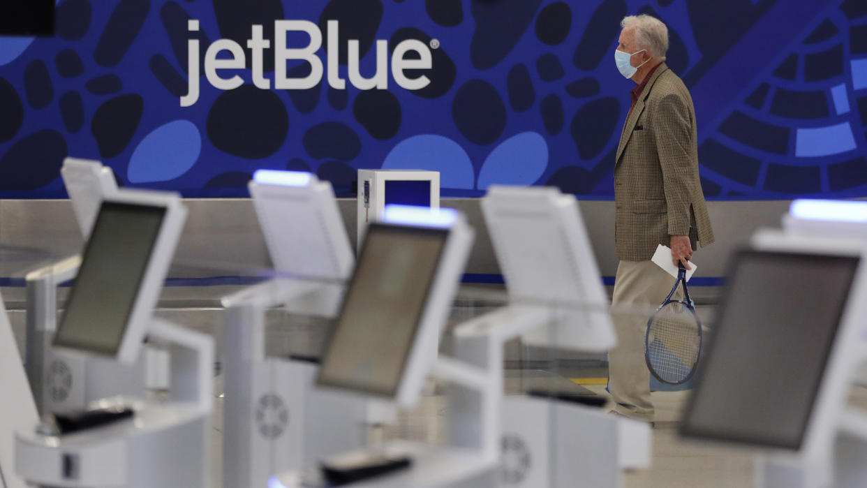 A traveler wearing a protective mask, due to the coronavirus outbreak, walks through the nearly empty JetBlue terminal at Logan Airport in Boston, Friday, May 29, 2020. JetBlue is further dialing back its growth plans after struggling with a high number of canceled flights. The company said Tuesday, April 26, 2022, that it lost $255 million in the first quarter but saw strong demand for travel, which pushed revenue higher. (AP Photo/Charles Krupa)