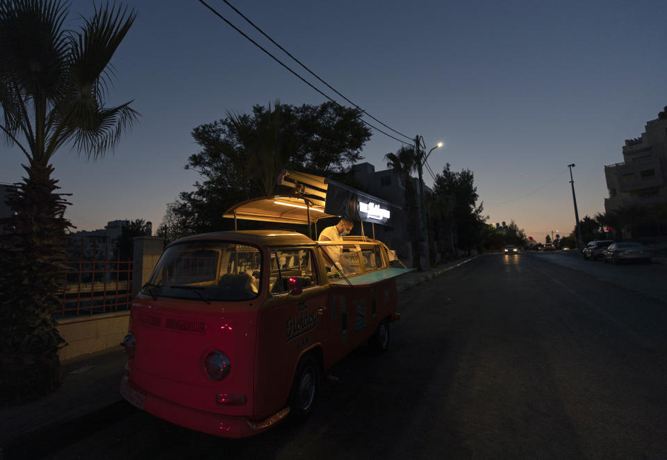 A man sells hot dogs and beverages out of a converted van in the West Bank city of Ramallah, Wednesday, Sept. 23, 2020. With dine-in restaurants mostly closed due to health restrictions, food trucks have allowed entrepreneurial Palestinian businessmen to find a way to keep working(AP Photo/Nasser Nasser)