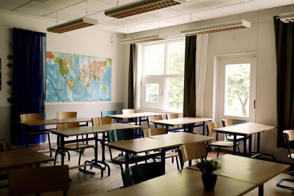 Empty classroom with desks, chairs, and a world map on the wall