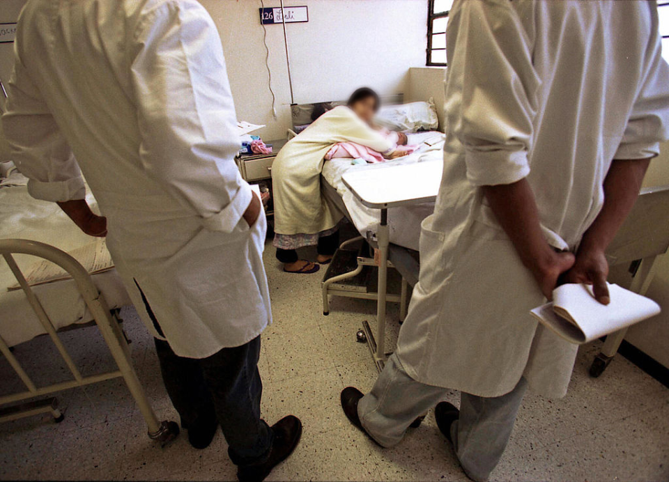 Dos doctores observan a una joven que atiende a su recién nacido en un hospital peruano. a su bebé en un  