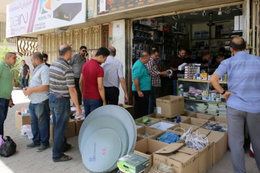 Iraqi men queue to buy satellite TV subscriptions in Baghdad on June 18, 2018, but most citizens cannot afford home pay TV packages