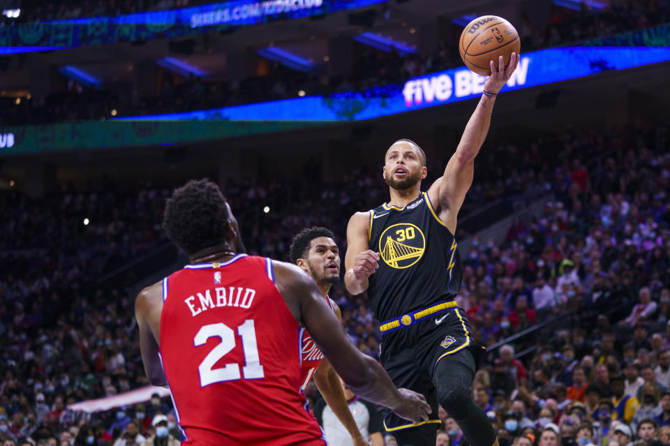 Golden State Warriors' Stephen Curry, right, goes up for the shot as Philadelphia 76ers' Joel Embiid, left, and Tobias Harris, center, look on during the first half of an NBA basketball game, Saturday, Dec. 11, 2021, in Philadelphia. (AP Photo/Chris Szagola)