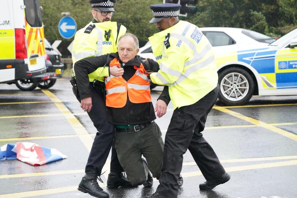 Police officers detain a protester from Insulate Britain occupying a roundabout leading from the M25 motorway to Heathrow Airport in London (Steve Parsons/PA) (PA Wire)