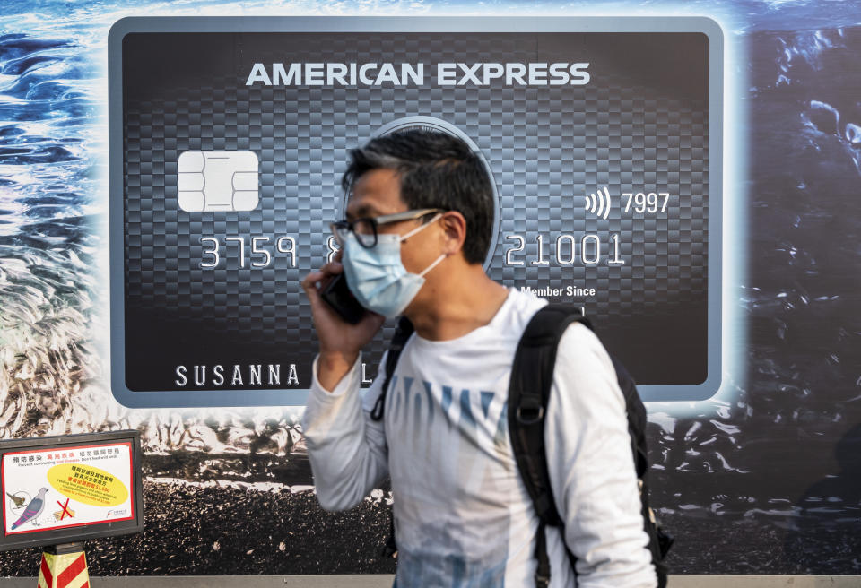 HONG KONG, CHINA - 2021/03/15: A pedestrian wearing a face mask walks past a commercial advertisement billboard of the American multinational financial services corporation and credit card business American Express in Hong Kong. (Photo by Budrul Chukrut/SOPA Images/LightRocket via Getty Images)