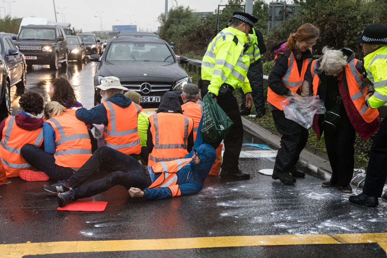 Metropolitan Police officers remove Insulate Britain climate activists from a M25 slip road at Junction 14 close to Heathrow airport which they had blocked as part of a campaign intended to push the UK government to make significant legislative change to start lowering emissions on 27th September 2021 in Colnbrook, United Kingdom. The activists are demanding that the government immediately promises both to fully fund and ensure the insulation of all social housing in Britain by 2025 and to produce within four months a legally binding national plan to fully fund and ensure the full low-energy and low-carbon whole-house retrofit, with no externalised costs, of all homes in Britain by 2030. (photo by Mark Kerrison/In Pictures via Getty Images)