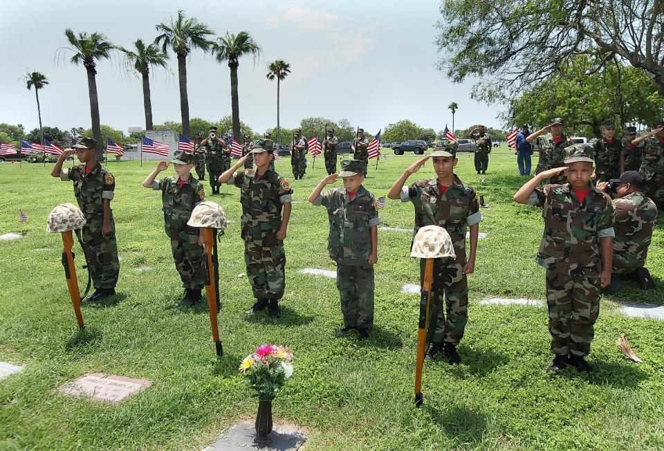 Young Marines honor the fallen while taps is played in the background at the conclusion of ceremonies at Memorial Day services at Seaside Memorial Park in Corpus Christi on Monday, May 30, 2016.