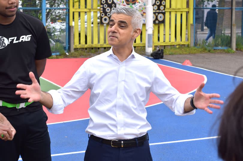 Sadiq Khan during a visit to BIGKID in Brixton wearing a white shirt and spreading his arms