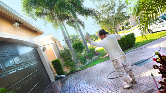 Hispanic male power washing an upscale home beore painting in a 55+ senior gated community.