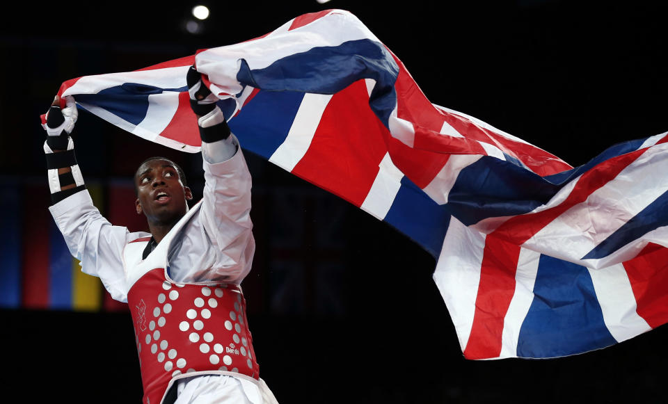 Britain's Muhammad Lutalo looks back at the Union flag he is carrying as he celebrates winning his men's -80kg bronze medal taekwondo match against Armenia's Arman Yeremyan at the London Olympic Games at the ExCeL venue August 10, 2012. REUTERS/Darren Staples (BRITAIN - Tags: SPORT OLYMPICS SPORT TAEKWONDO TPX IMAGES OF THE DAY) 