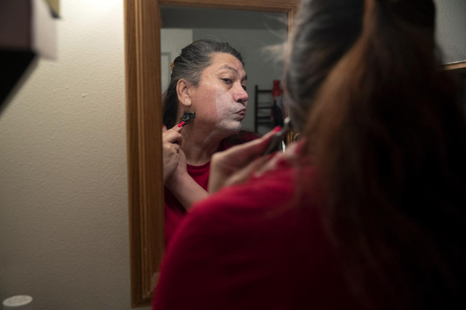 Christina Wood shaves before work in her home in Salem, Ore., Friday, April 21, 2023. Six years ago, Wood moved to Oregon, where she could access the gender-affirming health care she needed to live as her authentic self. Once there, Wood, was able to receive certain surgeries that helped her transition, but electrolysis, or permanent hair removal, wasn’t fully covered under the state’s Medicaid plan for low-income residents. Paying out-of-pocket ate up nearly half her monthly income, but it was critical for Wood's mental health. (AP Photo/Amanda Loman)