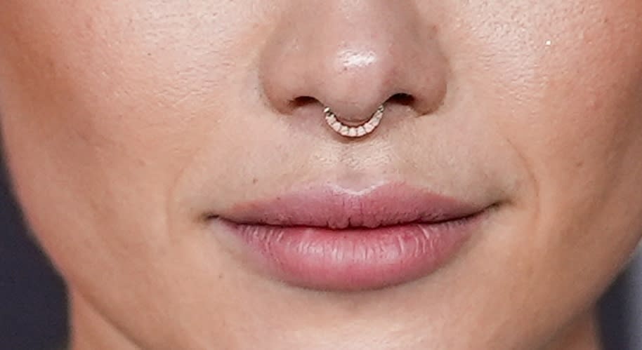 Close-up of a person's lips and nose with a small hoop septum piercing