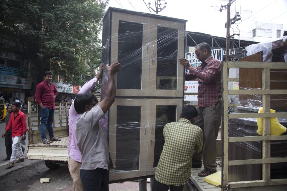In this Dec. 17, 2018, photo, workers unload a wardrobe from a truck at the Nampally furniture market in Hyderabad, India. This furniture market, where customers haggle over prices and work with carpenters to design made-to-order housewares, is the kind of competition Swedish giant Ikea faces in tackling the $40 billion Indian market for home furnishings, which is growing quickly along with the country’s consumer class. (AP Photo/Mahesh Kumar A.)