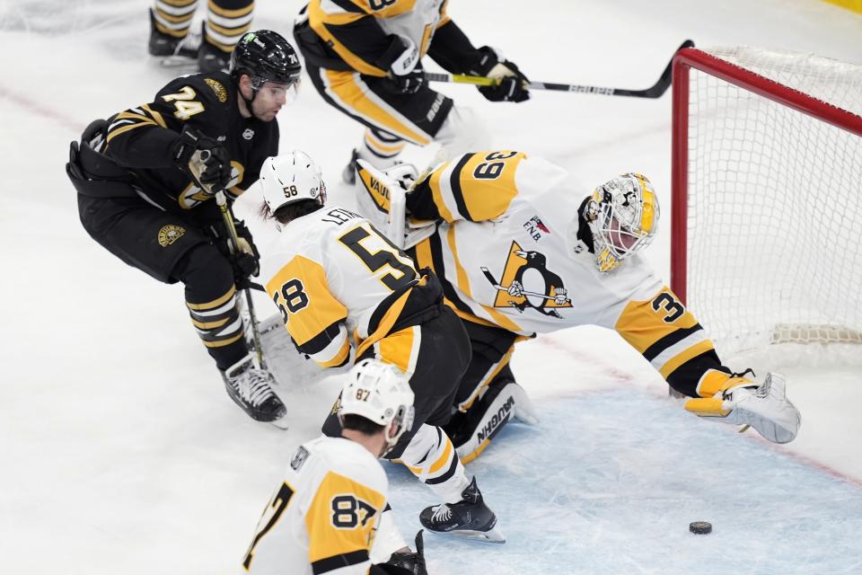 Pittsburgh Penguins' Alex Nedeljkovic (39) reaches for the puck in the crease under pressure from Boston Bruins' Jake DeBrusk (74) during the first period of an NHL hockey game, Saturday, March 9, 2024, in Boston. (AP Photo/Michael Dwyer)