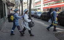 In this photo taken Saturday March 28, 2020, members of the Civil Protection service, Cyril Lamriben, right, and Noemie Biamba, left, escort to an ambulance a woman possibly infected with the Covid-19 virus in Paris. They don't have to put themselves in harm's way, but the volunteers of France's well-known Civil Protection service choose the front line in the fight against the coronavirus. They are often the first to knock on the doors of people calling for help, and who may have the infection or whose confirmed case has taken a downturn. (AP Photo/Michel Euler)