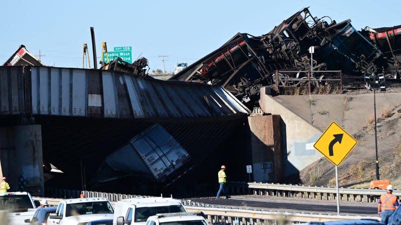 Authorities investigate the aftermath of a train derailment at mile marker 106 on Northbound I-25 north of Pueblo, Colorado on October 16, 2023. The highway likely will be shut down for several days- and potentially longer- after 30 cars derailed north of Pueblo, collapsing a rail bridge over the highway highway, state and federal officials said on Monday. A truck driver was killed when the bridge collapsed above the truck.