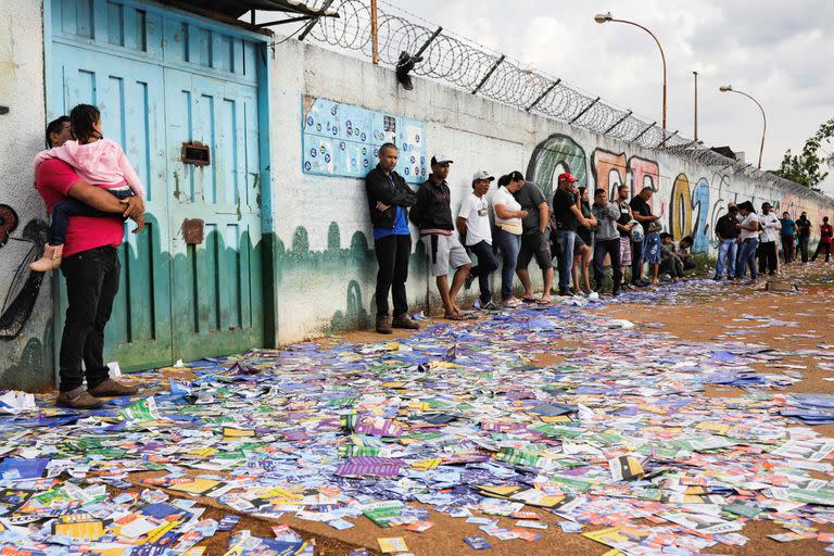 Los votantes esperan que se abra un centro de votación, con anuncios políticos en el suelo, durante las elecciones legislativas y presidenciales, en Brasilia, Brasil, el 2 de octubre de 2022. - La votación comenzó el domingo temprano en la economía más grande de América del Sur, plagada de enormes desigualdades y violencia, donde se espera que los votantes elijan entre el titular de extrema derecha Jair Bolsonaro y el favorito de izquierda Luiz Inácio Lula da Silva, cualquiera de los cuales debe obtener el 50 por ciento de los votos válidos, más uno, para ganar en la primera vuelta. (Foto de Sergio Lima / AFP)