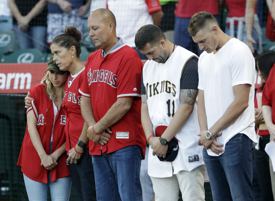 CORRECTS MOTHER'S LAST NAME TO HETMAN, INSTEAD OF SKAGGS - CORRECTS NAME OF PERSON AT MIDDLE - Members of Tyler Skaggs' family, including wife, Carli, left; mother, Debbie Hetman, second from left; and Danny Hetman, third from left, join in a moment of silence in Tyler's honor before the Los Angeles Angels' baseball game against the Seattle Mariners on Friday, July 12, 2019, in Anaheim, Calif. (AP Photo/Marcio Jose Sanchez)