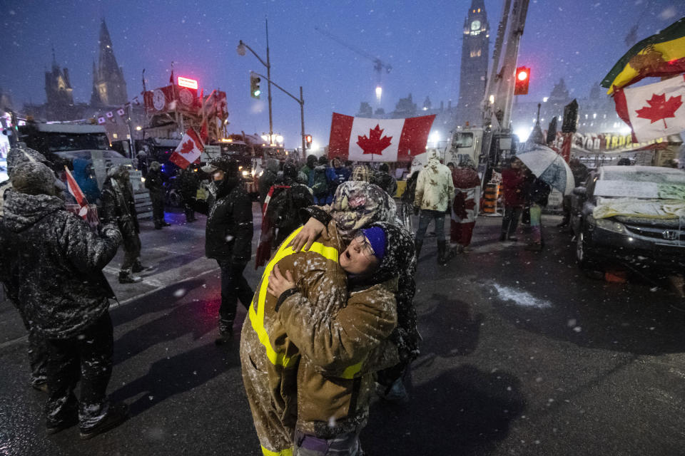 Protesters dance and embrace as a song plays over the speakers, during an ongoing protest against COVID-19 measures that has grown into a broader anti-government protest, in Ottawa, Ontario, on Thursday, Feb. 17, 2022. (Justin Tang/The Canadian Press via AP)