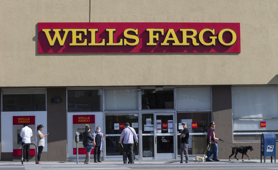 Customer, some wearing face masks, line up outside a Wells Fargo branch in the Atwater Village neighborhood of Los Angeles on Friday, April 3, 2020, during the coronavirus outbreak. (AP Photo/Damian Dovarganes)