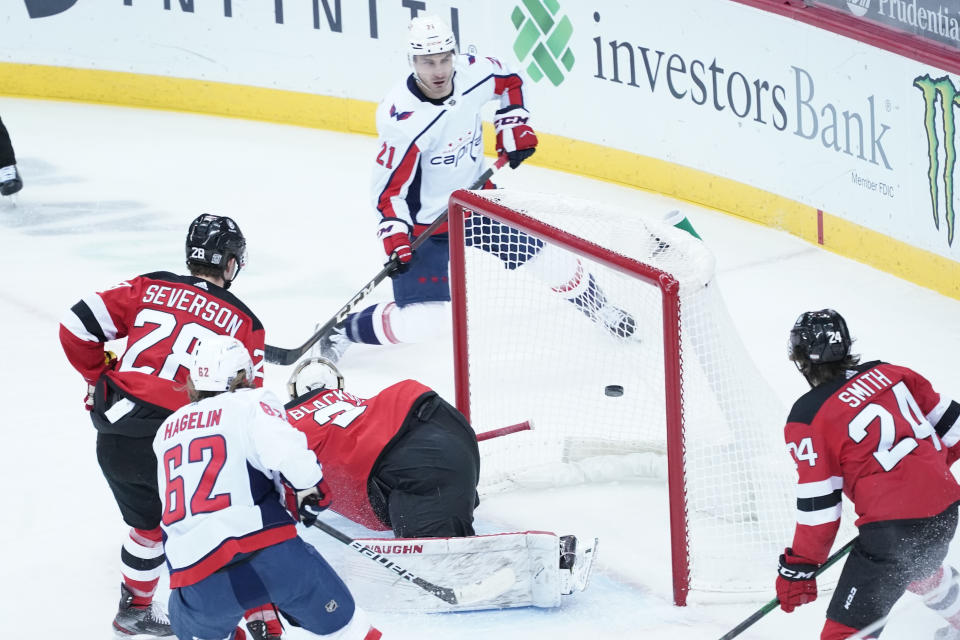 Washington Capitals right wing Garnet Hathaway (21) scores a goal past New Jersey Devils goaltender Mackenzie Blackwood (29) during the first period of an NHL hockey game, Saturday, Feb. 27, 2021, in Newark, N.J. (AP Photo/Mary Altaffer)