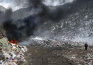 A trash collector walks at the burning landfill near Priboj, in southwest Serbia, Friday, Jan. 22, 2021. Serbia and other Balkan nations are virtually drowning in communal waste after decades of neglect and lack of efficient waste-management policies in the countries aspiring to join the European Union. (AP Photo/Darko Vojinovic)