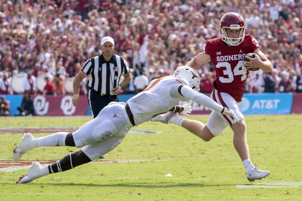 Oklahoma kicker Zach Schmit (34) runs for a first down past Texas linebacker DeMarvion Overshown (0) on a fake field goal during the first half of an NCAA college football game at the Cotton Bowl, Saturday, Oct. 8, 2022, in Dallas. (AP Photo/Jeffrey McWhorter)