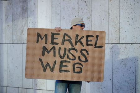 A protestor holds a placard reading "Merkel must go" outside the CDU headquarters during a Christian Democratic Union (CDU) leadership meeting in Berlin, Germany July 1, 2018. REUTERS/Axel Schmidt