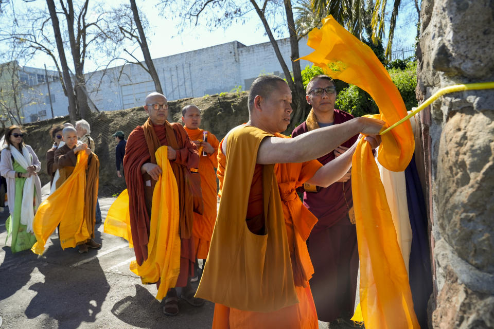 Khammai Sayakoummane, center, places a Tibetan scarf on the Birthplace of Antioch marker during the "May We Gather" pilgrimage, Saturday, March 16, 2024, in Antioch, Calif. The event aimed to use karmic cleansing through chants, prayer and testimony to heal racial trauma caused by anti-Chinese discrimination in Antioch in the 1870s. (AP Photo/Godofredo A. Vasquez)