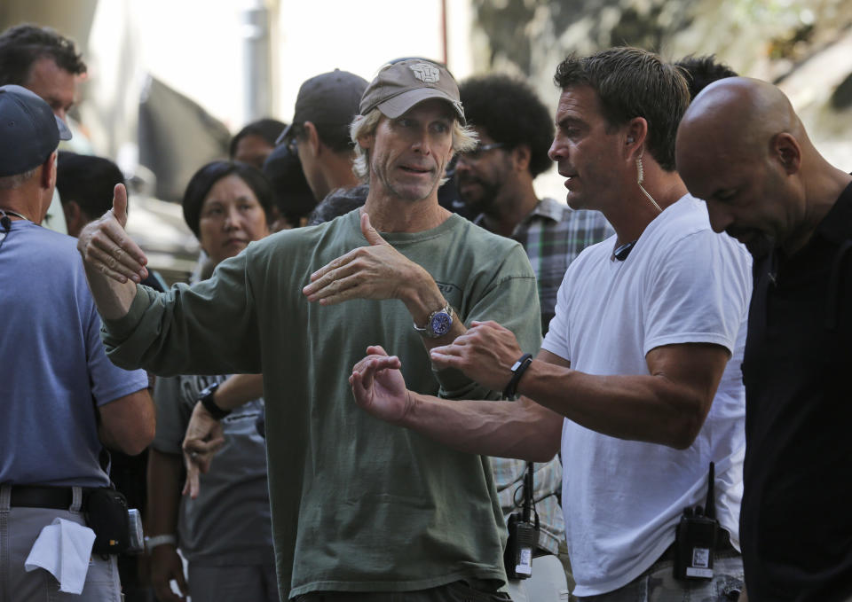 American film director Michael Bay, center, talks with his film crew during the filming of a scene for their latest movie "Transformers 4: Age of Extinction" in Hong Kong Friday, Oct. 18, 2013. Bay was attacked on Thursday and slightly injured on the set of the fourth installment of the "Transformers" movie series filming in Hong Kong, police said. The spokeswoman said Bay suffered a minor injury to his face but declined medical treatment. (AP Photo/Kin Cheung)