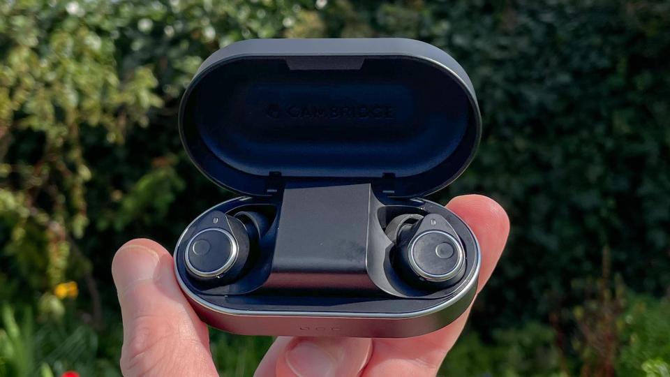 Cambridge Audio Melomania M100 in charging case held in hand in a yard