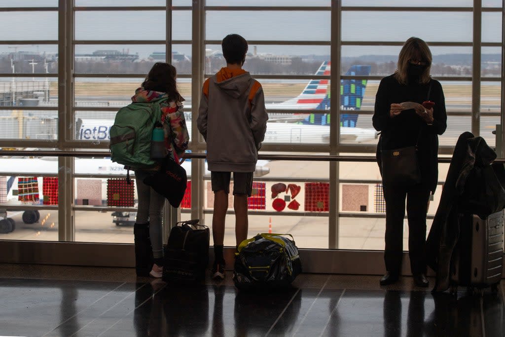 File: Travelers watch planes on the tarmac near checking in counters at Ronald Reagan International Airport in Washington, DC on 27 December 2021 (AFP via Getty Images)