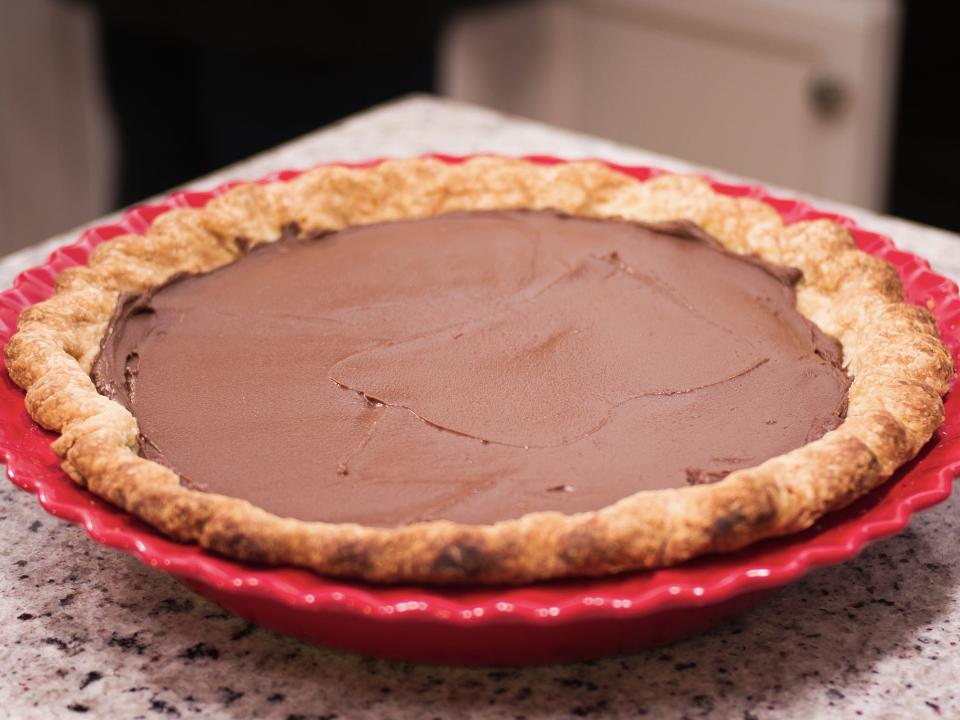 chocolate cream pie in red pie pan on granite countertop