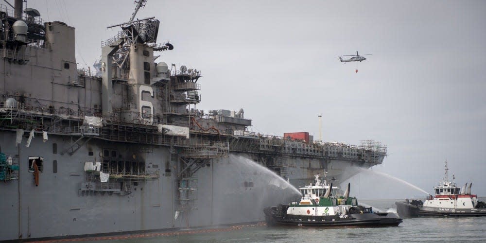 An MH-60S Sea Hawk helicopter from Helicopter Sea Combat Squadron (HSC) 3 alongside Federal San Diego Firefighters combat a fire aboard the amphibious assault ship USS Bonhomme Richard (LHD 6)