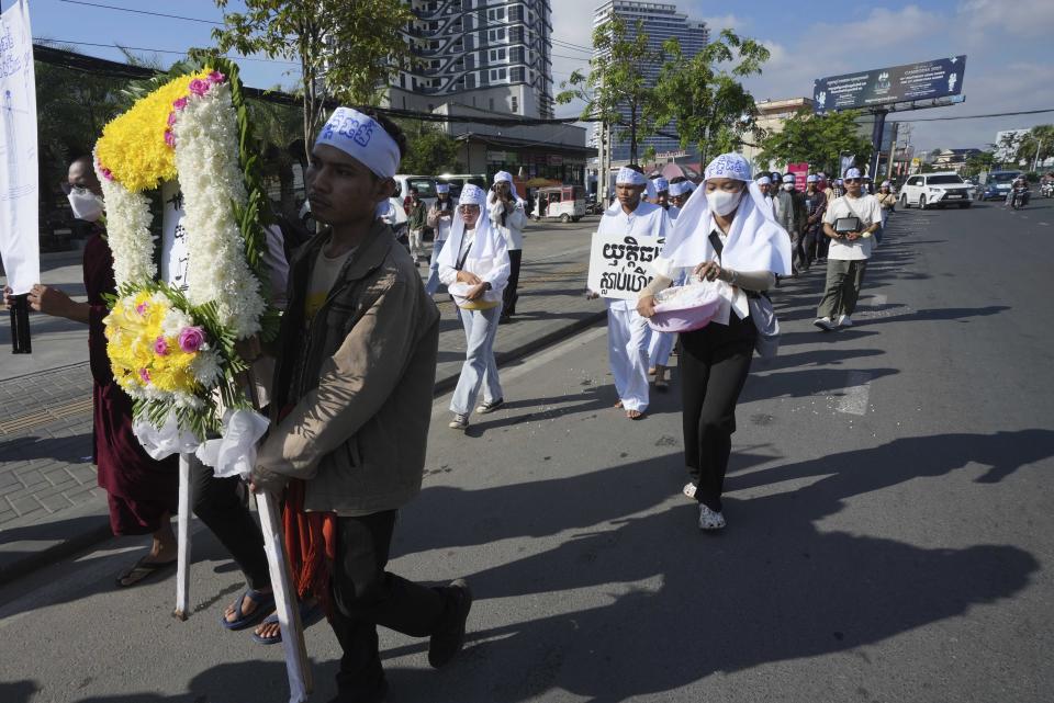 Environmental activists march on a main street as they head to Phnom Penh Municipality Court, in Phnom Penh, Cambodia, Tuesday, July 2, 2024. Ten members of a nonviolent environmental activist group in Cambodia were convicted on Tuesday on charges of conspiracy to commit a crime, receiving prison sentences of six years each. The words in a flower frame is read "Justice". (AP Photo/Heng Sinith)