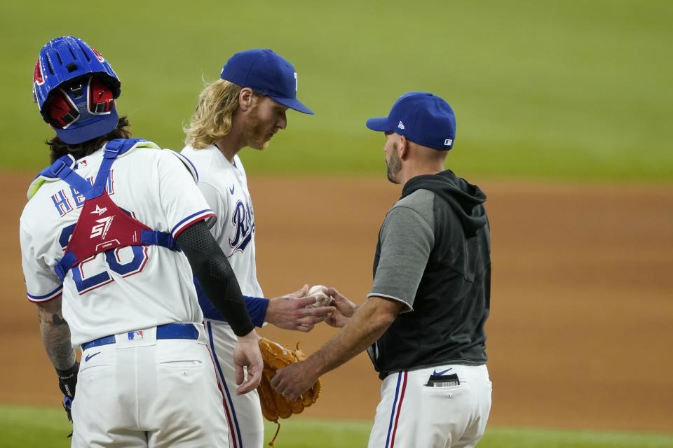 Texas Rangers catcher Jonah Heim, left, stands by as starting pitcher Mike Foltynewicz, center, turns the ball over to manager Chris Woodward, right, in the seventh inning of a baseball game against the Oakland Athletics in Arlington, Texas, Saturday, July 10, 2021. (AP Photo/Tony Gutierrez)