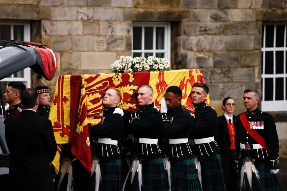 Pallbearers carry the coffin of late Britain's Queen Elizabeth II covered with the Royal Standard of Scotland, at the Palace of Holyroodhouse, in Edinburgh on September 11, 2022. - Queen Elizabeth II's coffin will travel by road through Scottish towns and villages on Sunday as it begins its final journey from her beloved Scottish retreat of Balmoral. The Queen, who died on September 8, will be taken to the Palace of Holyroodhouse before lying at rest in St Giles' Cathedral, before travelling onwards to London for her funeral.. (Photo by ALKIS KONSTANTINIDIS / POOL / AFP) (Photo by ALKIS KONSTANTINIDIS/POOL/AFP via Getty Images)